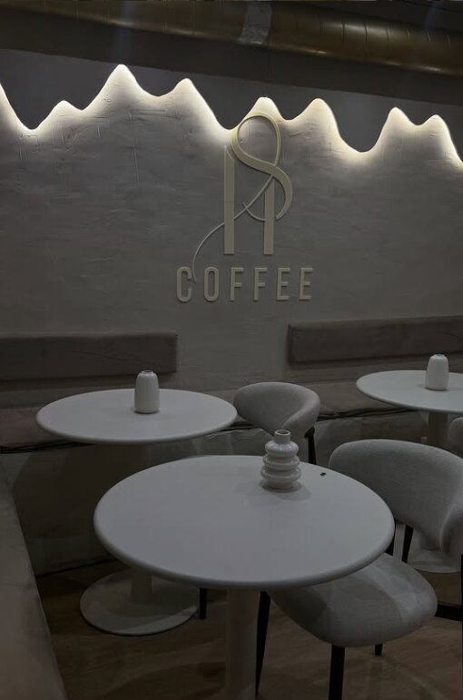 Tables rondes devant le mur au logo SH Coffee éclairé